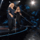 a woman in a blue dress is standing on a stage holding a microphone