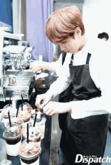 a man in an apron is preparing drinks in plastic cups with straws in front of a sign that says dispatch