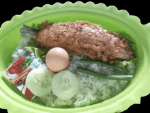 a green bowl of food with a packet of strawberry sauce