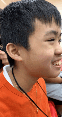 a young boy wearing a lanyard around his neck smiles for the camera