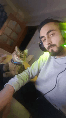 a man wearing headphones is holding a cat on his lap