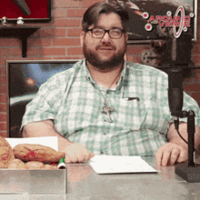 a man in a plaid shirt is sitting in front of a microphone in front of a sign that says carolina radio