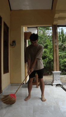 a man is sweeping the floor with a broom in front of a yellow building