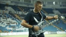 a man playing a guitar in a stadium with a shirt that says ' eagle ' on it