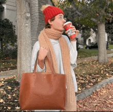 a woman wearing a red hat and scarf is holding a starbucks cup