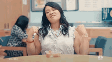 a woman is sitting at a table with her arms outstretched and a bowl of food on her lap .