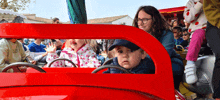 a group of people are riding in a red toy car