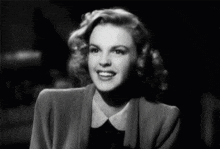 a black and white photo of a smiling woman in a suit and collared shirt .