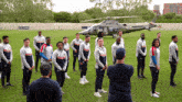 a group of men standing on a field with a helicopter in the background and a sign that says ' no smoking '