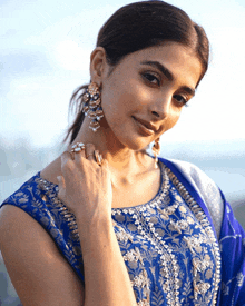 a close up of a woman wearing a blue top and gold earrings