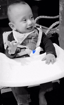 a baby is sitting in a high chair with a blue toy