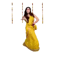 a woman in a yellow sari dancing on a swing