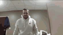 a man wearing a white nike hoodie is standing in a room