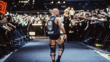 a wrestler with the name bullet proof on his back walks through a crowd