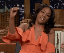 a woman in an orange dress is sitting in front of a sign that says tonight