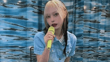 a young woman is holding a yellow microphone in front of a blue curtain .