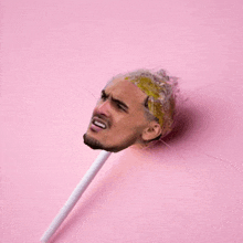 a lollipop with a man 's face on it on a pink background