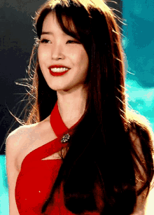 a woman in a red dress is smiling and looking at the camera