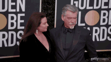 a man and a woman are standing on a red carpet in front of a sign that says golden globe awards