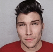 a close up of a man 's face wearing a red shirt and smiling .