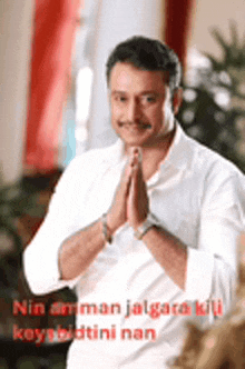 a man in a white shirt is praying with his hands folded in front of him .