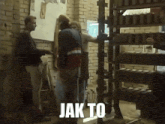 a group of people standing in front of a brick wall with the word jak to on the bottom