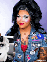 a drag queen wearing a denim jacket has a flamingo pin on her chest