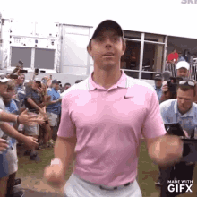 a man in a pink shirt is standing in front of a crowd of people and a sign that says made with gifx