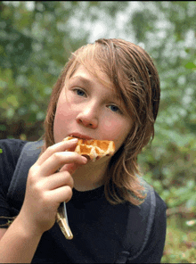 a boy with long hair is eating a waffle with a fork