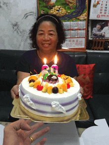 a woman is holding a cake with candles on it in front of a calendar that says ' chinese calendar ' on it