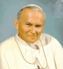 a close up of a man wearing a white robe with a gold chain around his neck