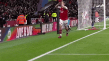 a soccer player celebrates after scoring a goal in front of a banner that says " love is love "