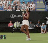 a woman holding a tennis racquet in front of a lexus banner