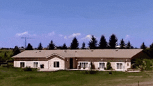 a large house sits in the middle of a grassy field surrounded by trees