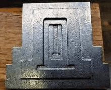 a piece of metal is sitting on a wooden surface .