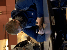 a man wearing a blue under armour jacket sits at a table