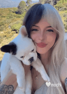 a woman holding a black and white puppy with the word mochi on the bottom right