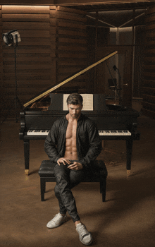 a shirtless man sits on a bench in front of a grand piano