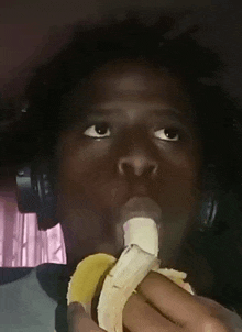 a man wearing headphones is eating a banana with his tongue out .