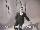 a man in a suit and tie is dancing in a room with the words stuck in louisville .