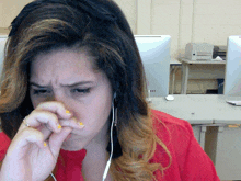 a woman covering her nose with her hand while wearing ear buds