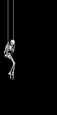 a skeleton is hanging from a rope and looking down .