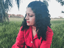 a woman in a red shirt is sitting in a field