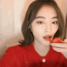 a woman in a red sweater is eating a piece of food .