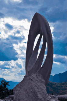 a large stone sculpture with mountains in the background and a cloudy sky