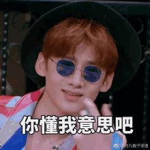 a young man wearing sunglasses and a hat is making a funny face in chinese .