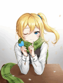 a girl with blonde hair wearing a green scarf and holding a heart