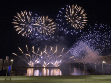 a fireworks display over a river with a bridge in the background