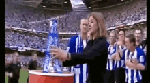 a group of people in blue and white striped shirts are standing in a stadium with a woman standing in front of them