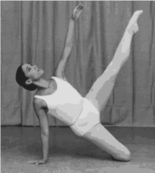 a black and white photo of a female ballet dancer doing a split